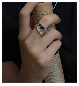 Gros plan d'une bague large ondulée en argent S925 avec finition miroir poli sur main
