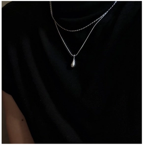 Detail of double-layer S925 silver necklace with teardrop pendant and beaded chain texture