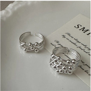 Close-up of S925 sterling silver multilayer beaded rings on a decorative ceramic plate