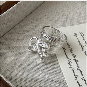 Macro shot of silver bow ring featuring bark texture and adjustable open band detail