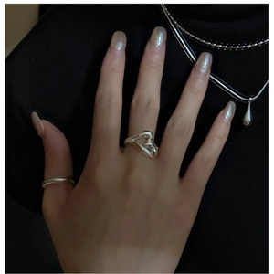 Detail of layered silver heart rings and drop pendant necklace on a black turtleneck