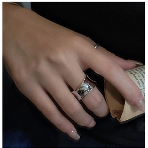 Gros plan d'une bague large argentée minimaliste polie portée par un mannequin