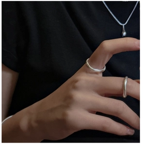 Detail of S925 sterling silver matte rings and teardrop pendant on black fabric background