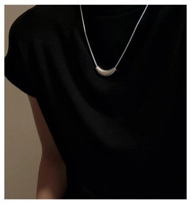 Detail of silver curved minimalist pendant on a sleek snake chain worn on the neck