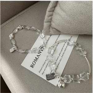 Close-up of S925 silver crystal bracelets with engraved pendants on romantic background