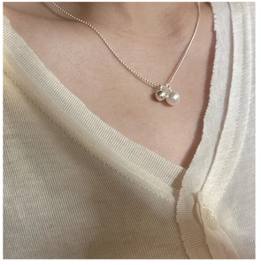 Detail of S925 silver necklace featuring a white shell pearl and a small metallic bead