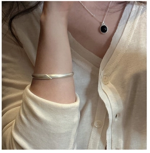 Close-up of a matte S925 silver bangle and necklace with a black round pendant