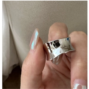 Vue macro d'une bague large incurvée en argent S925 avec une finition polie miroir épurée