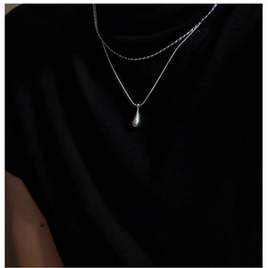 Detail of layered S925 sterling silver necklace with minimalist water drop pendant on neck
