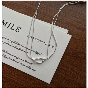 Detail einer silbernen zweilagigen Schlangenkette mit minimalistischem Knoten-Design