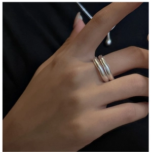 Close-up of a double-layered wavy silver ring with a polished finish worn on a hand