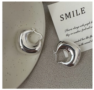 Macro shot of chunky S925 sterling silver C-shaped hoop earrings with a mirror finish