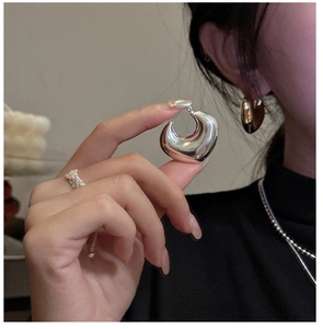 Close-up of chunky silver C-shape earrings with a high-polished mirror finish