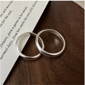 Close-up of matte silver rings showing delicate brushed texture on a wooden stand