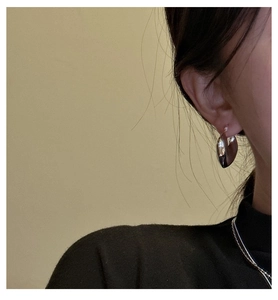 Close-up of polished silver heart earrings worn by a model in a minimalist style