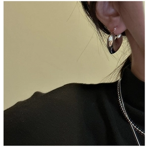Close-up of chunky S925 sterling silver hollow heart earrings worn by a model