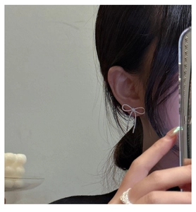 Macro shot of S925 silver bow earrings with twisted metal texture on female model