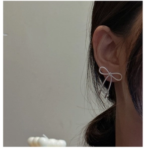 Close-up of S925 silver bow earrings with textured rope design worn by a model