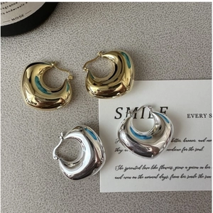 Macro shot of polished S925 sterling silver hollow hoop earrings in gold and silver finish