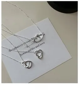 Close-up of S925 silver double heart necklaces on a white decorative card