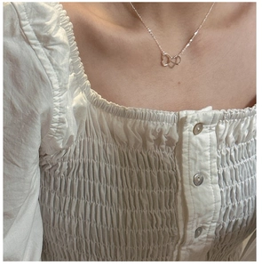 Detail of S925 sterling silver double heart necklace worn on a woman's collarbone