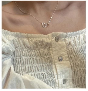 Close-up of interlocking heart necklace in S925 sterling silver worn by a female model
