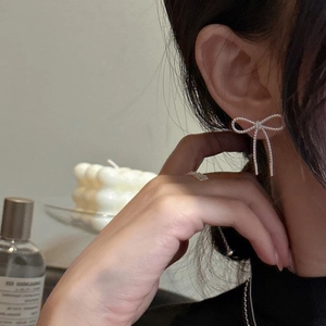 Minimalist S925 sterling silver bow earrings with rope chain texture worn by a model