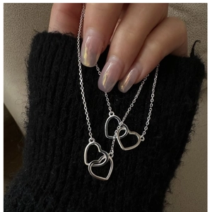 Macro shot of double heart pendant necklace in S925 sterling silver on a black knit background