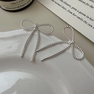 Elegant S925 sterling silver bow earrings with twisted rope texture in a ceramic tray