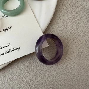 Detail view of natural amethyst and green jade rings with smooth polished finish