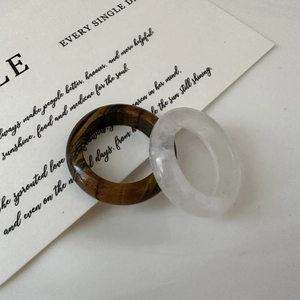 Detailed view of wide band natural tiger eye and white quartz stone rings on a card