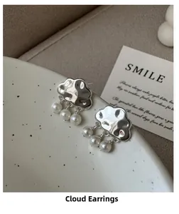 Detail of silver cloud earrings with pearl raindrops on a ceramic plate edge