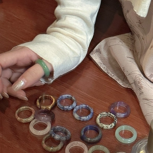 Minimalist natural stone rings collection in assorted colors shown on wooden surface