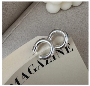 Macro shot of silver C-shaped chunky hoop earrings with a high-polished mirror finish