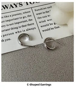 Detailed close-up of S925 sterling silver stamp on minimalist C-shaped hoop earrings