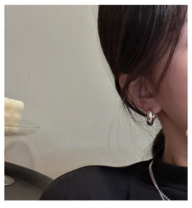 Macro view of glossy S925 silver C-shape earrings worn for a stylish minimalist look