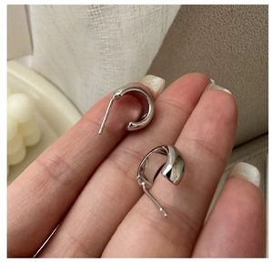 Macro shot of minimalist S925 sterling silver curved hook earrings with a polished finish