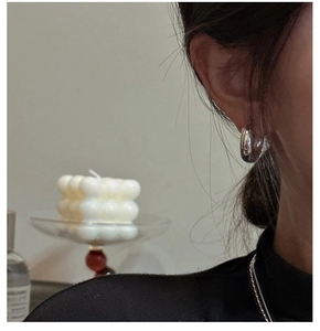 Close-up of chunky S925 sterling silver hoop earrings worn for a minimalist modern look