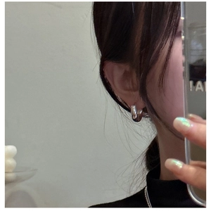 Close-up of chunky silver hoop earring with high-polish mirror finish on person