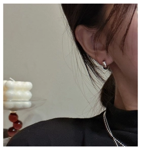 Close-up of minimalist S925 sterling silver small hoop earrings on model wearing black knit