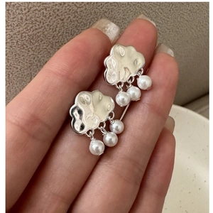 Detail of S925 silver cloud earrings with hammered texture and dangling white pearls