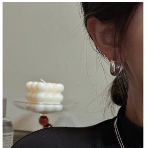 Close-up of minimalist chunky silver hoop earrings worn on a model in a cozy setting