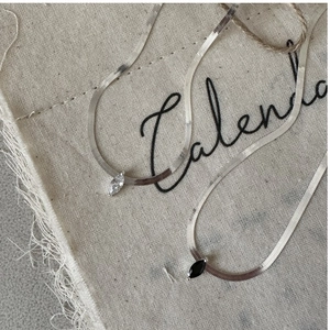 Détails de colliers en argent S925 avec zircons noirs et blancs sur fond en tissu naturel