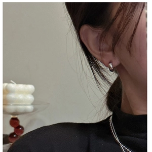 Close-up of small polished S925 silver hoop earring worn on ear with minimalist style