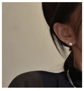 Close-up of a 6-8mm white round pearl stud earring with soft luster worn on a model ear
