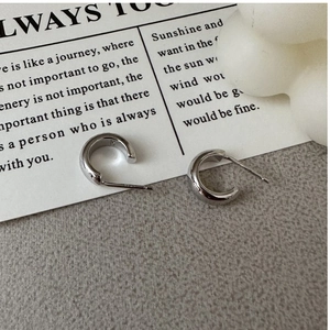 Detail of S925 sterling silver C-shape hoop earrings with polished finish on a display base