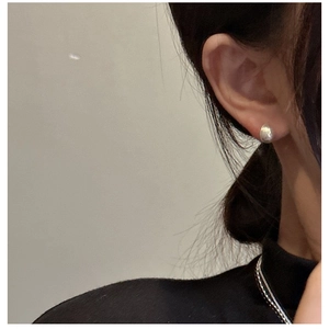Close-up of minimalist S925 sterling silver drop stud earrings with a brushed metallic finish