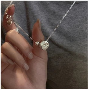 Makroaufnahme einer S925 Sterlingsilber Kette mit texturiertem Münzanhänger und Gravur