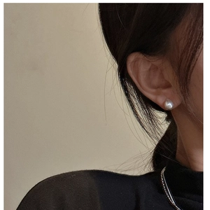 Close-up of 8mm white pearl stud earrings on model for a minimalist jewelry style
