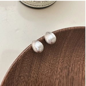 Macro view showing brushed silver waterdrop earrings with minimalist matte texture